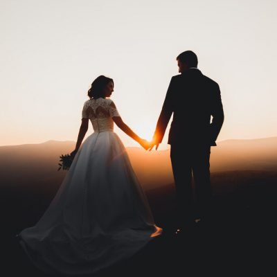 Wedding couple walking on bridge near lake on sunset at wedding day. Bride and groom in love.